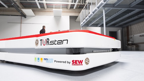 White automated guided vehicle system labelled with the word "TORsten" and the SEW‑EURODRIVE logo